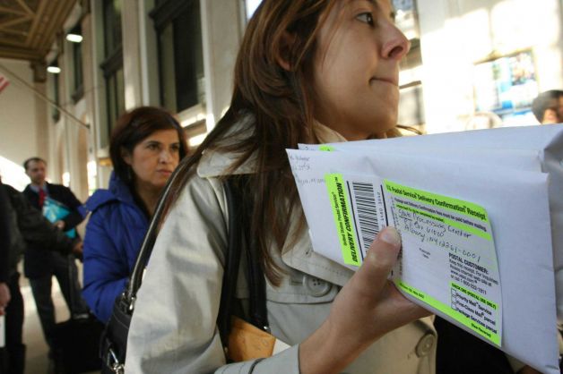 FILE - In this April, 15, 2008, file photo, Dana Pinero, of New York, foreground, waits in line to mail tax returns for both herself and her boyfriend at the James A. Farley Main Post Office in New York. The package of tax increases and spending cuts known as the fiscal cliff takes effect on January 1, 2013, unless Congress passes a budget deal by then. The economy would be hit so hard that it would likely sink into recession in the first half of 2013, economists say. Photo: Tina Fineberg / AP